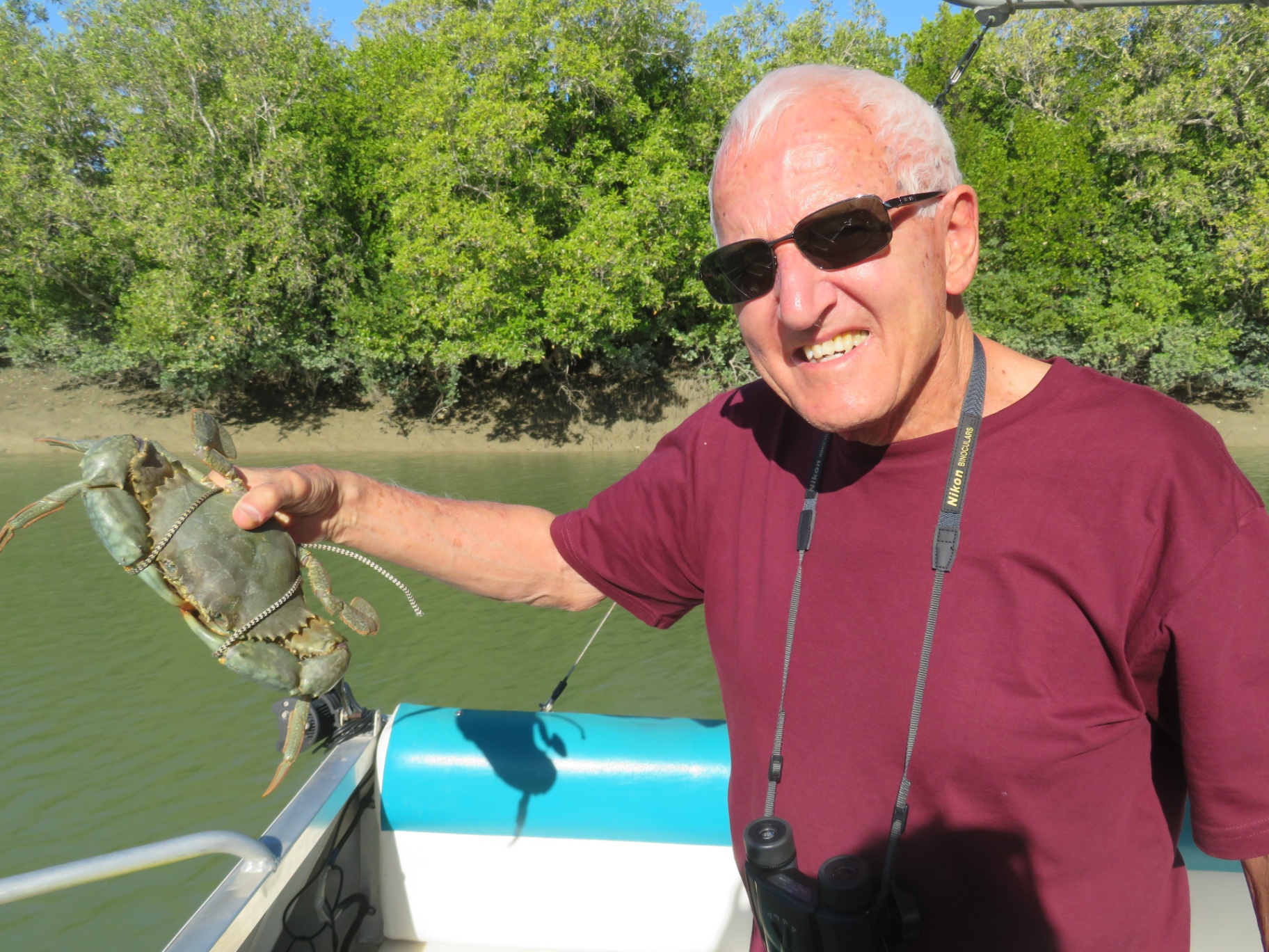 Ron Pitcher holding a freshly caught mud crab on a tropical river cruise