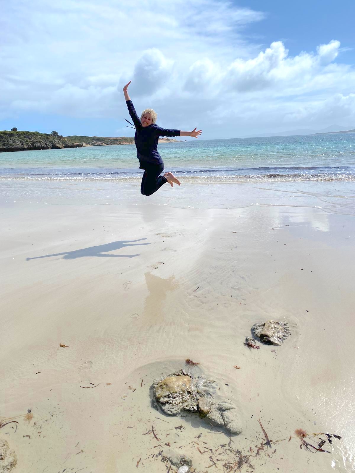 Air Adventure guest leaping for joy on a remote white-sand beach